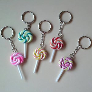 May include: A collection of six colorful lollipop keychains. Each keychain features a swirled lollipop design in various colors, including pink, green, yellow, and red, attached to a silver keyring with a chain.