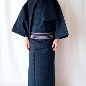 May include: A dark blue Japanese yukata, a casual summer kimono, with a matching obi belt. The yukata features wide sleeves and a wrap-around design. The obi belt is a contrasting color with a striped pattern.