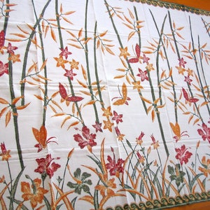 May include: White fabric with a repeating pattern of brown bamboo stalks, orange and red flowers, and butterflies. The fabric has a green border with a wave pattern.