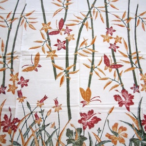 May include: White fabric with a repeating pattern of brown bamboo stalks, orange and yellow flowers, and red butterflies. The fabric has a green border with a wavy design.
