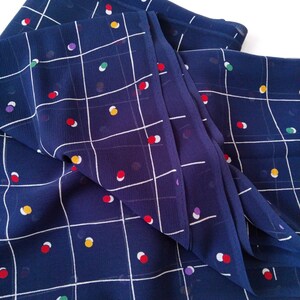 May include: Blue fabric with a white grid pattern and colorful polka dots. The fabric is folded and has a slight sheen.
