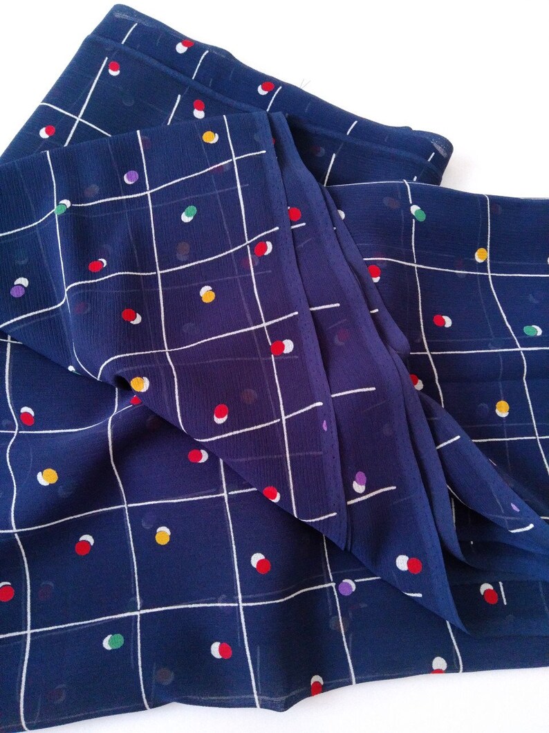 May include: Blue fabric with a white grid pattern and colorful polka dots. The fabric is folded and has a slight sheen.