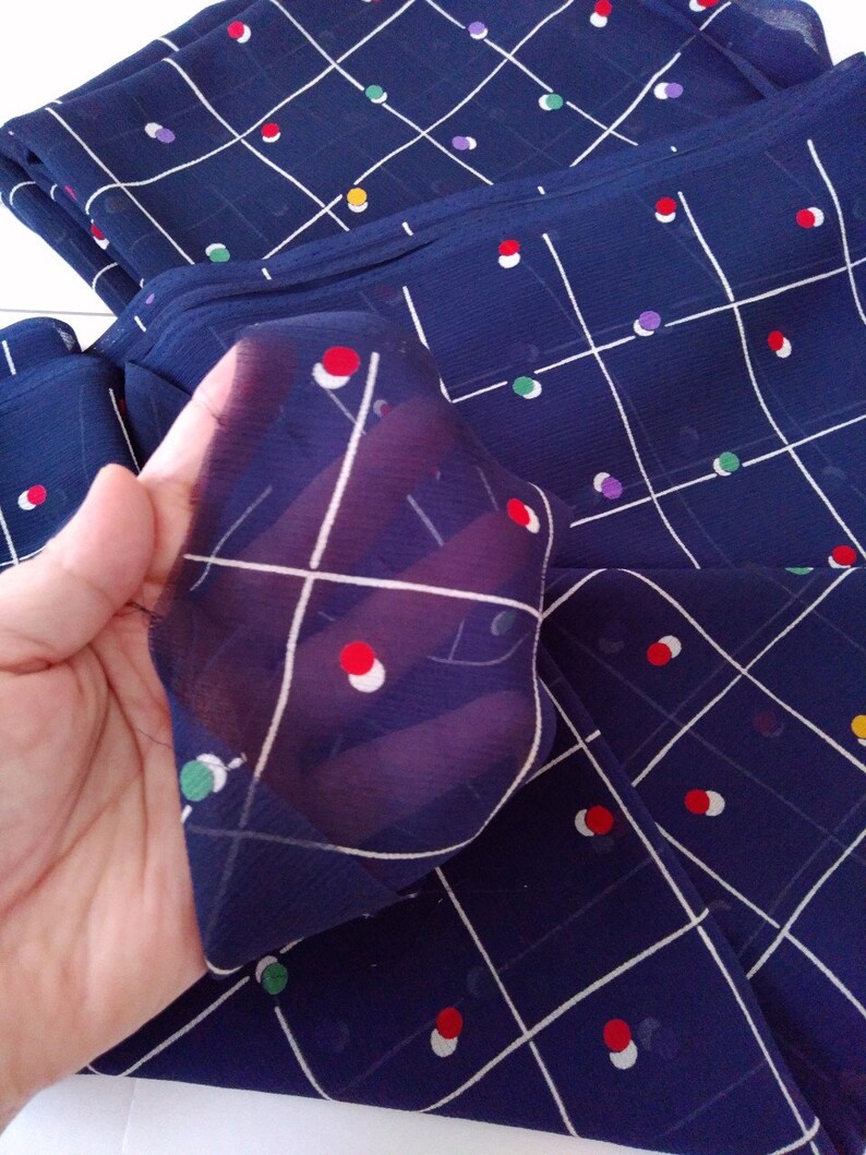May include: Navy blue fabric with a white grid pattern and colorful circles. The fabric is sheer and has a soft, flowing texture.