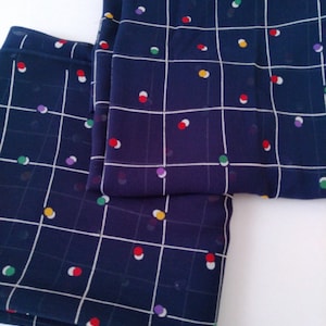 May include: Two pieces of navy blue fabric with a white grid pattern and colorful polka dots.