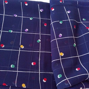 May include: A folded piece of navy blue fabric with a white grid pattern and colorful polka dots.