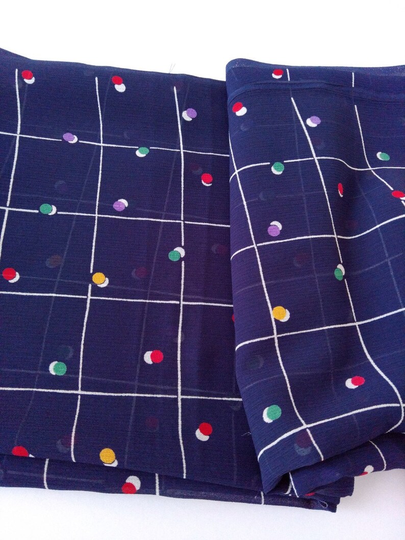 May include: A folded piece of navy blue fabric with a white grid pattern and colorful polka dots.