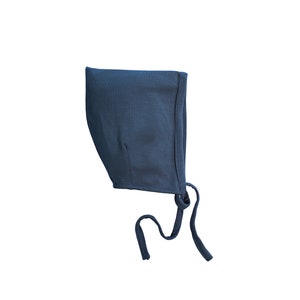 May include: A dark blue baby bonnet with a tie string. The bonnet is made of a soft, stretchy fabric.