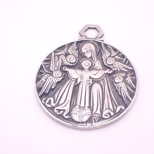 May include: A silver-colored pendant with a religious theme. The pendant features a detailed relief of a woman holding a child, surrounded by angels. The design is circular with a hexagonal loop at the top for hanging.
