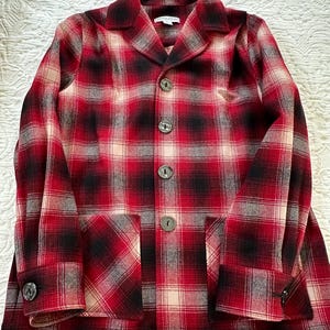 May include: Red, black, and white plaid flannel jacket with a button closure and a single patch pocket. The label reads "Evolution".