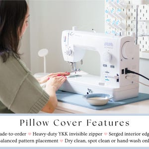 May include: A white sewing machine is on a light blue mat on a white table. The machine is in use, with a person's hands visible. The image includes the text "Pillow Cover Features".