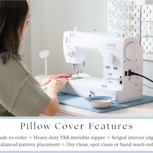 May include: A white sewing machine on a light blue mat, with a person in the background. The machine is plugged in and ready for use. A small bowl sits on the mat. The image includes the text "Pillow Cover Features".