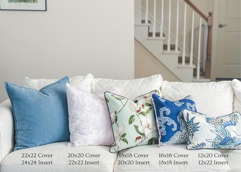 May include: A collection of decorative throw pillows in various sizes and designs, including solid blue, floral, and patterned options. Sizes range from 12x20 inches to 22x22 inches. The pillows are arranged on a white sofa, offering a range of textures and colors.