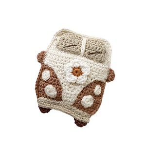May include: A crocheted plush toy shaped like a vintage van with brown and white polka dots and a white flower on the front.