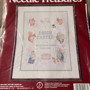 May include: A cross-stitch kit titled "Needle Treasures" featuring a Beatrix Potter sampler. The design includes embroidered images of squirrels, rabbits, and other characters, with the name "ROBIN CARTER" and the date "DECEMBER 19, 1987". The kit includes floss and instructions.