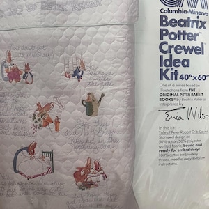 May include: A Beatrix Potter Crewel Idea Kit featuring a stamped design of Peter Rabbit illustrations. The kit includes a 40" x 60" quilted fabric crib cover, embroidery thread, and needle. The design includes embroidered images and text from the story.