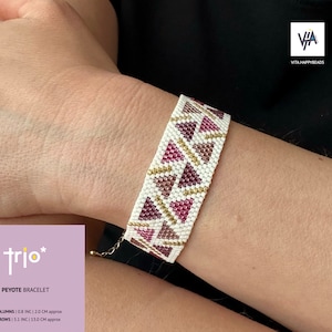 Op de afbeelding: Wit peyote-steek armband met een geometrisch patroon van roze, gouden en witte driehoeken. De armband is 13,0 cm lang en 2,0 cm breed. De armband is gemaakt met kralen en heet "trio*"