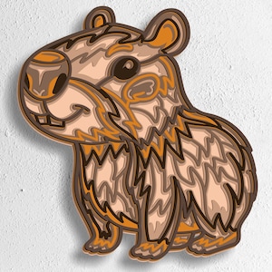 May include: A layered wooden art piece depicting a smiling capybara in shades of brown, tan, and orange. The design features intricate details and is mounted on a white background. The bottom of the image displays the text "SVG - EPS - DWG - DXF - AI".
