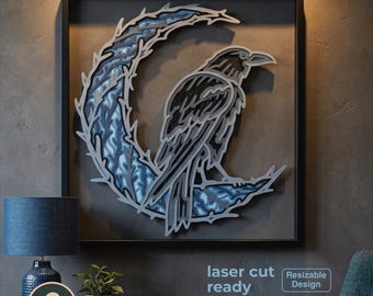 May include: A multi-layered laser-cut wall art piece featuring a black raven perched on a crescent moon with blue and grey textured patterns. The artwork is framed in black and includes text stating 6 layers, laser cut ready, and resizable design.