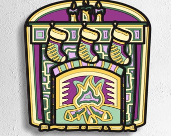 May include: A layered papercraft design of a fireplace with three stockings hanging from the mantel and a fire burning in the hearth. The fireplace is decorated with a yellow, green, and purple colour scheme.