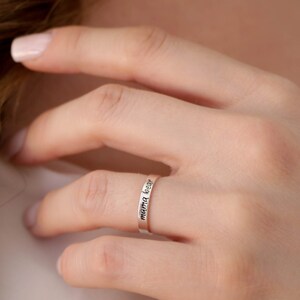 May include: A silver ring inscribed with the words "mamma kiss".