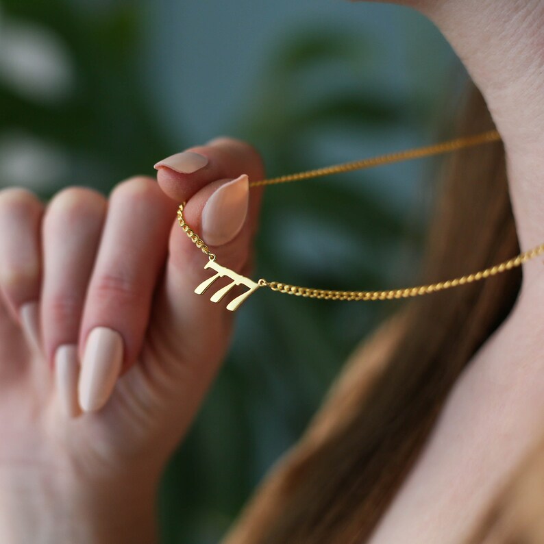 May include: A gold chain necklace with a pendant featuring the number 777.