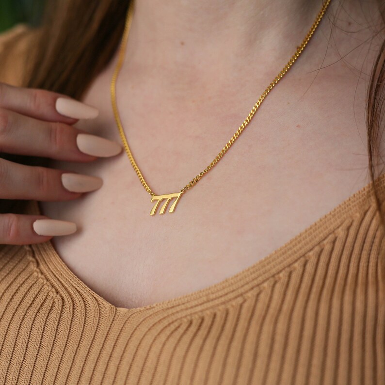May include: A gold chain necklace with a pendant featuring the number 777.