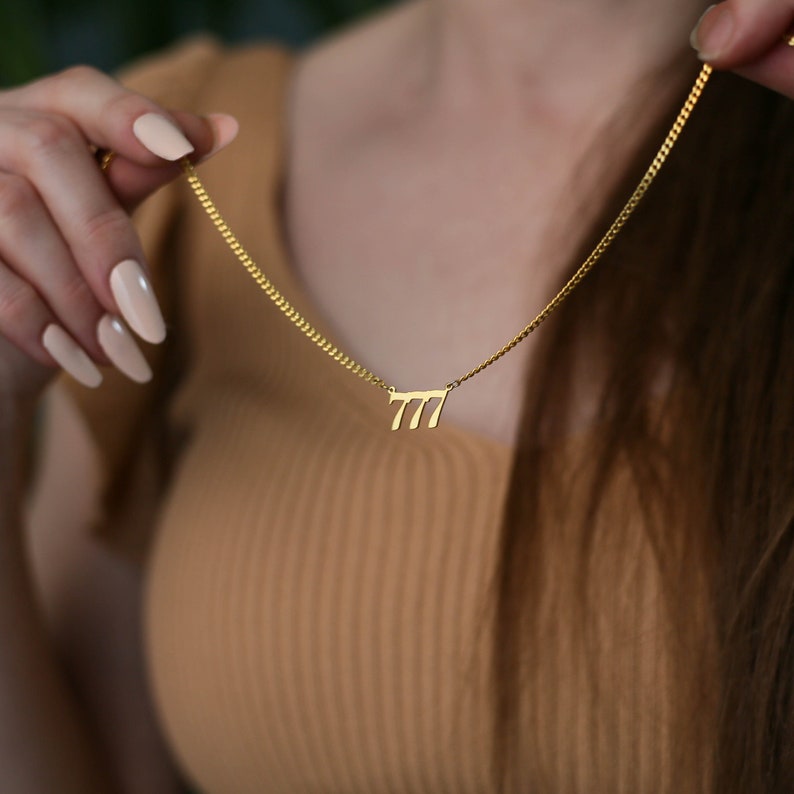 May include: A gold chain necklace with a pendant featuring the number 777.