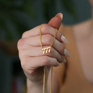 May include: A gold chain necklace with a pendant shaped like the number 777.