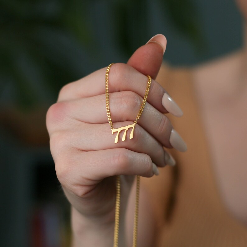 May include: A gold chain necklace with a pendant shaped like the number 777.