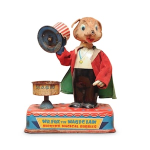 Puede incluir: Un juguete de hojalata vintage de Mr. Fox el Mago soplando burbujas mágicas. El juguete está hecho de metal y tiene un esquema de color rojo, verde y negro. El juguete está en buen estado y tiene algunas señales de desgaste. El juguete es un gran ejemplo de juguetes vintage.