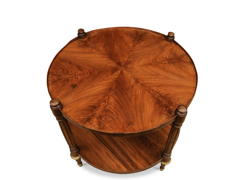 May include: A round, two-tiered wooden table with a starburst pattern on the top. The table has a dark brown finish and gold accents on the legs.