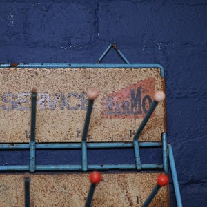 May include: A blue metal rack with hooks for hanging items. The rack has a sign that says "Car Service Remarkable".