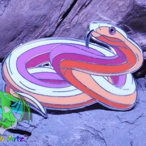 May include: A colorful enamel pin of a snake curled up in a circle. The snake is white with orange, pink, and red stripes. The pin has a silver finish.