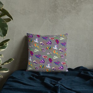 May include: A gray throw pillow with a colorful, repeating pattern of abstract shapes resembling worms or snakes. The shapes are in various colors, including pink, purple, blue, green, yellow, and red.