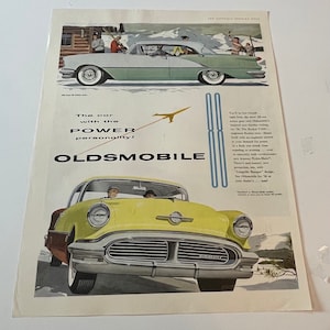 May include: A vintage advertisement for Oldsmobile cars. The ad features two yellow and green Oldsmobile cars with the tagline "The car with the POWER personality!"