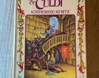 May include: A vintage paperback book titled "Camber of Culdi" by Katherine Kurtz. The cover features a detailed illustration of a medieval battle scene with figures in armor, swords, and a spiral staircase. The book is Volume I in the Legends of Camber of Culdi.