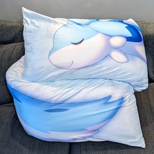 K&ouml;nnte beinhalten: Zwei blaue und wei&szlig;e Kissenbez&uuml;ge mit einem Cartoon-Fisch-Design. Der Fisch hat ein geschlossenes Auge und einen hellblauen K&ouml;rper mit einem wei&szlig;en Bauch.