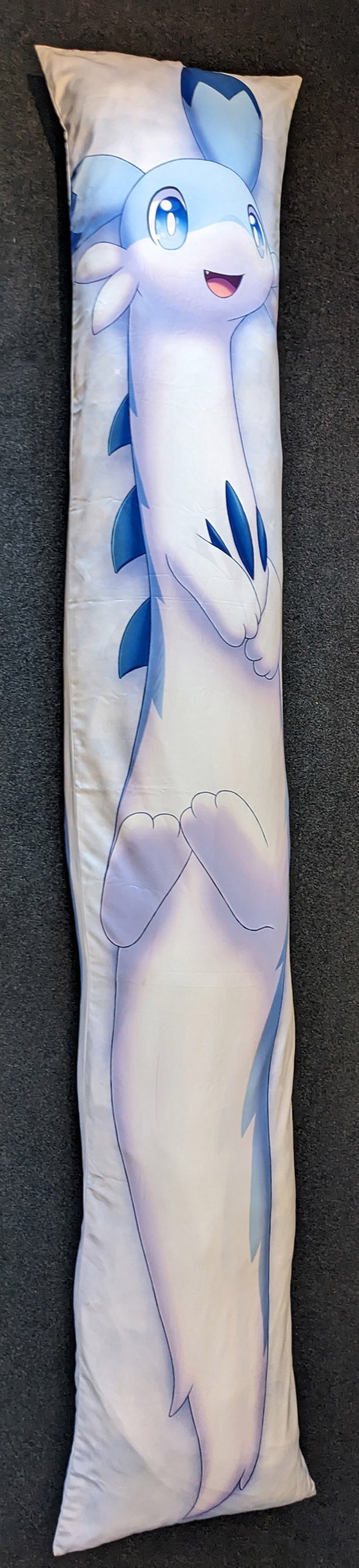 K&ouml;nnte beinhalten: Ein wei&szlig;es und blaues Kissen mit einem Cartoon-Charakter einer langen, schlanken, blau&auml;ugigen Kreatur mit blauen Flossen und einem hellblauen Schwanz.