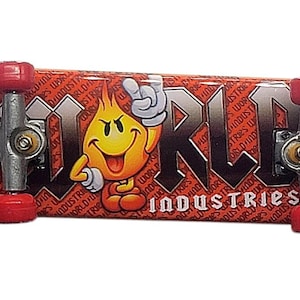 May include: A red and black World Industries finger skateboard with red wheels. The board features the text "WORLD INDUSTRIES" and a cartoon flame character. The background has a repeating pattern of the words "WORLD INDUSTRIES".