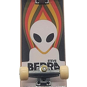May include: A miniature skateboard with a black top featuring an alien graphic and the text "STEVE BEARD". The wheels are beige, and the board has a gray bottom with the text "CARRY THE TORCH".
