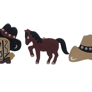 May include: Three wooden cowboy-themed cutouts. A black cowboy hat with rhinestones, a brown horse, and a tan cowboy hat with rhinestones. The cowboy boot cutout is tan and black with rhinestone accents.