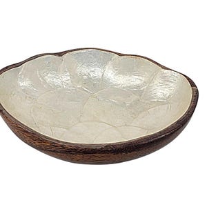 May include: Oval-shaped decorative bowl with a dark brown wooden exterior and a pearlescent, white interior. The bowl's interior is made of small, irregularly shaped pieces, creating a textured surface. The bowl is designed for decorative purposes.