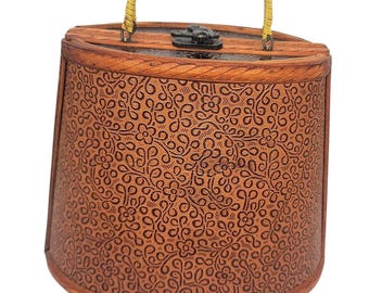 May include: A vintage brown handbag with a floral pattern. The bag has a rounded shape with a yellow handle and a black clasp. The exterior is made of a textured material with a repeating floral design.
