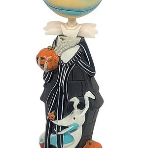 May include: A figurine of Jack Skellington from The Nightmare Before Christmas, holding a pumpkin. The figure has a round head with blue eye sockets and a stitched smile. Zero the ghost dog is also featured. The base reads "Jack & Zero."
