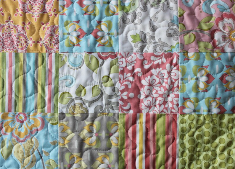 May include: A patchwork quilt with a variety of floral and geometric patterns in shades of pink, blue, green, and yellow.