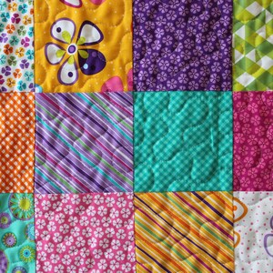 Pu&ograve; includere: Un quilt patchwork con quadrati di diversi colori e motivi, tra cui arancione, giallo, viola, rosa, verde e blu. Il quilt &egrave; realizzato in tessuto con motivi floreali, geometrici e a righe.