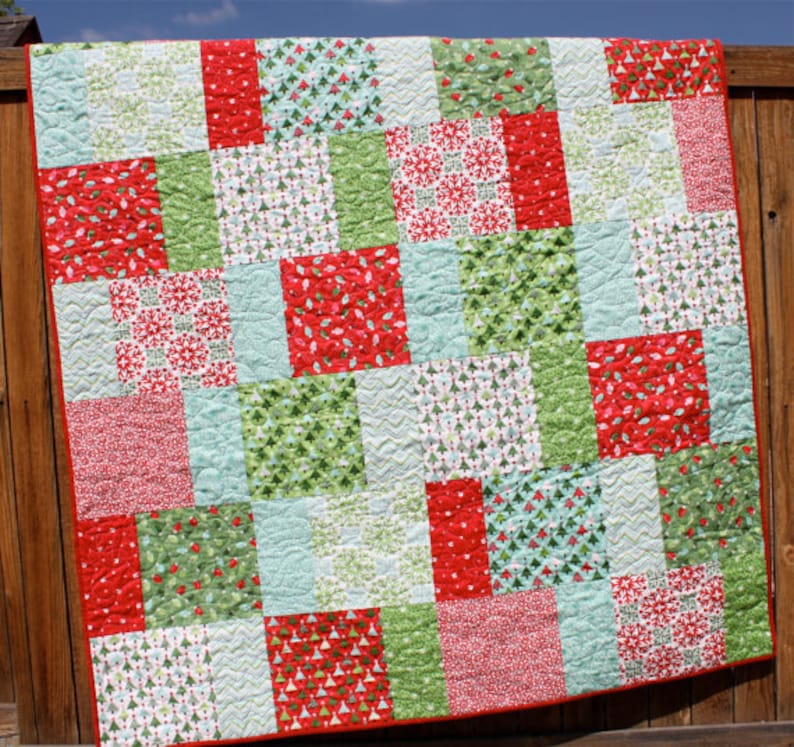 May include: A red, green, and white patchwork quilt with a variety of Christmas-themed patterns. The quilt is made of squares and rectangles, and it is quilted with a simple stitch.