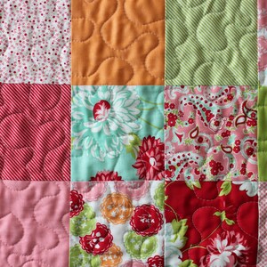 May include: A patchwork quilt featuring a range of floral and geometric patterns in shades of pink, green, orange, and blue.