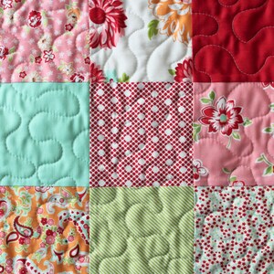 May include: A patchwork quilt featuring a range of floral patterns in shades of pink, red, green, and white. The quilt is made from different fabrics with various quilting stitches.