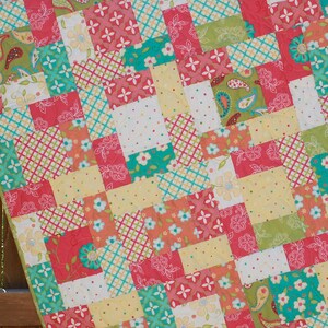 May include: A patchwork quilt with a variety of colorful squares in shades of pink, green, yellow, and blue. The squares feature different patterns, including floral, paisley, and geometric designs.
